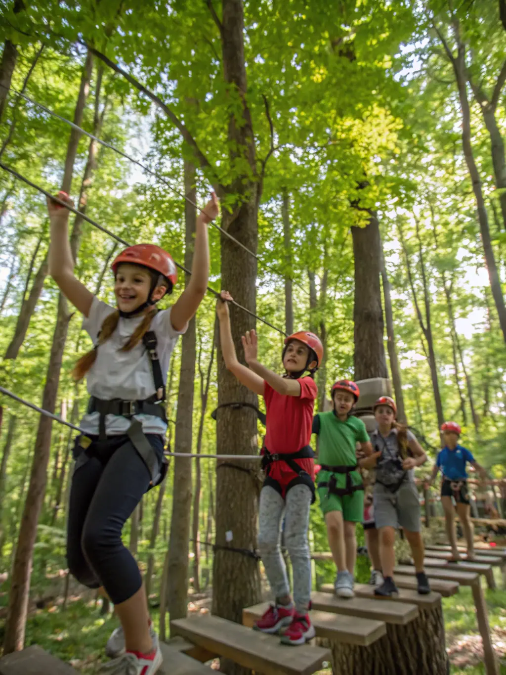 A group of children and adults wearing harnesses and helmets, climbing a tall, healthy tree in a lush forest setting, with smiles and a sense of adventure.